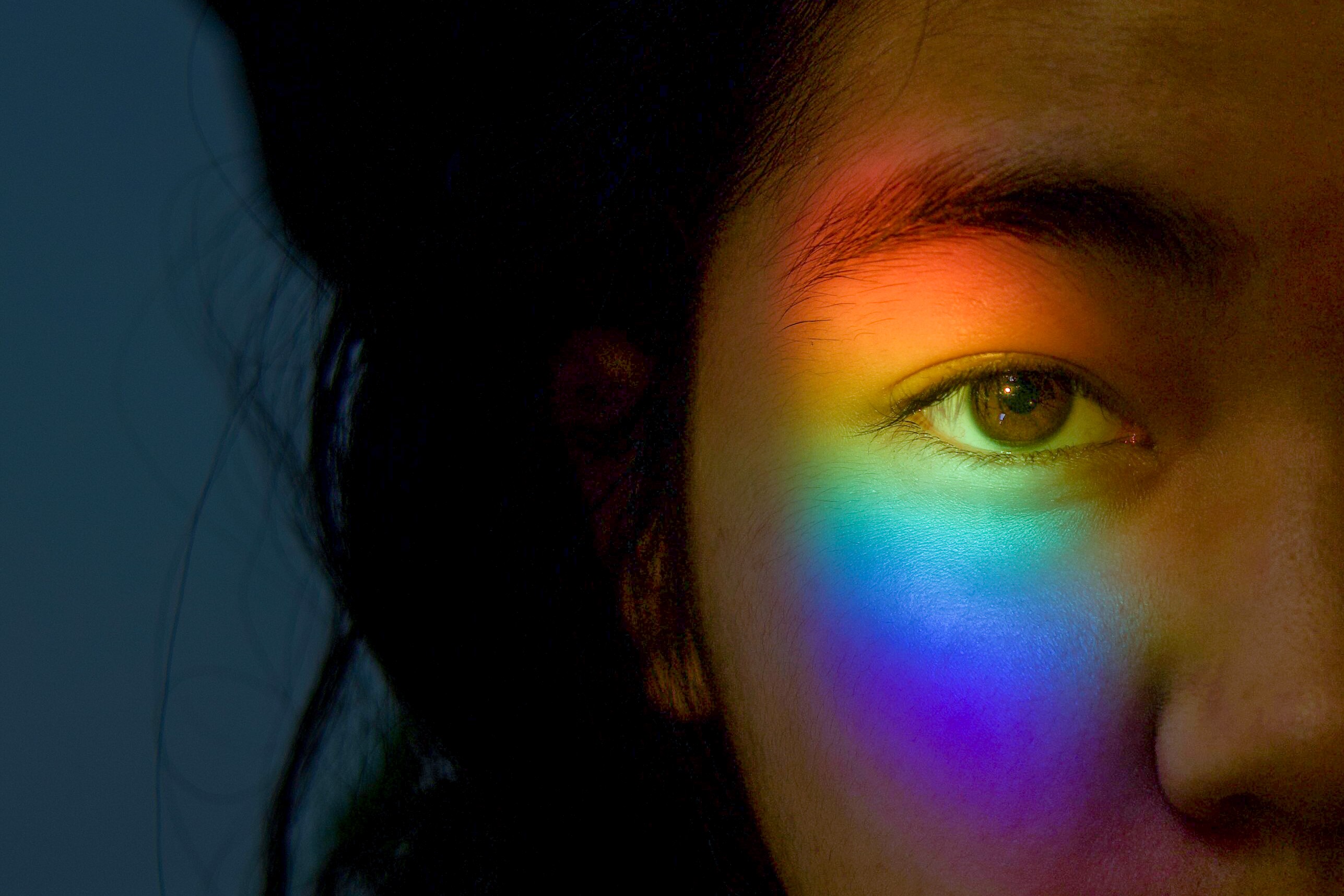 Child with a prismatic rainbow over their eye