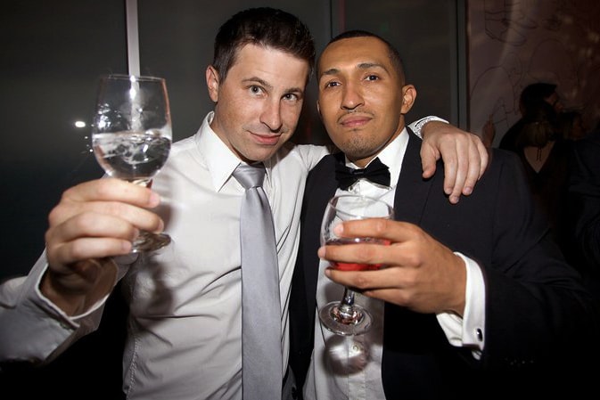 Two well-dressed men holding up drinks in celebration